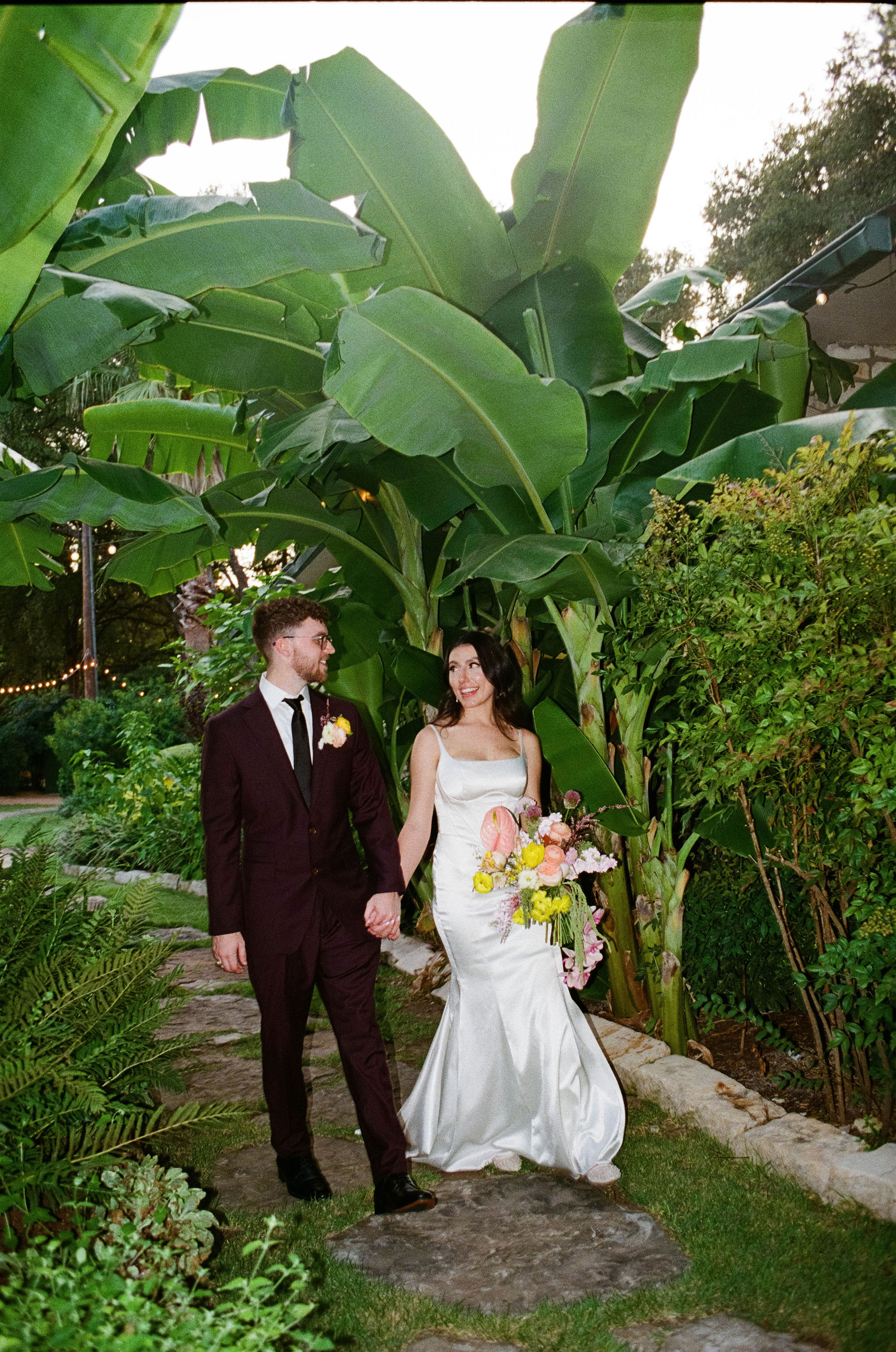 Couple walking under palm leaves at Hummingbird House in Austin, Texas