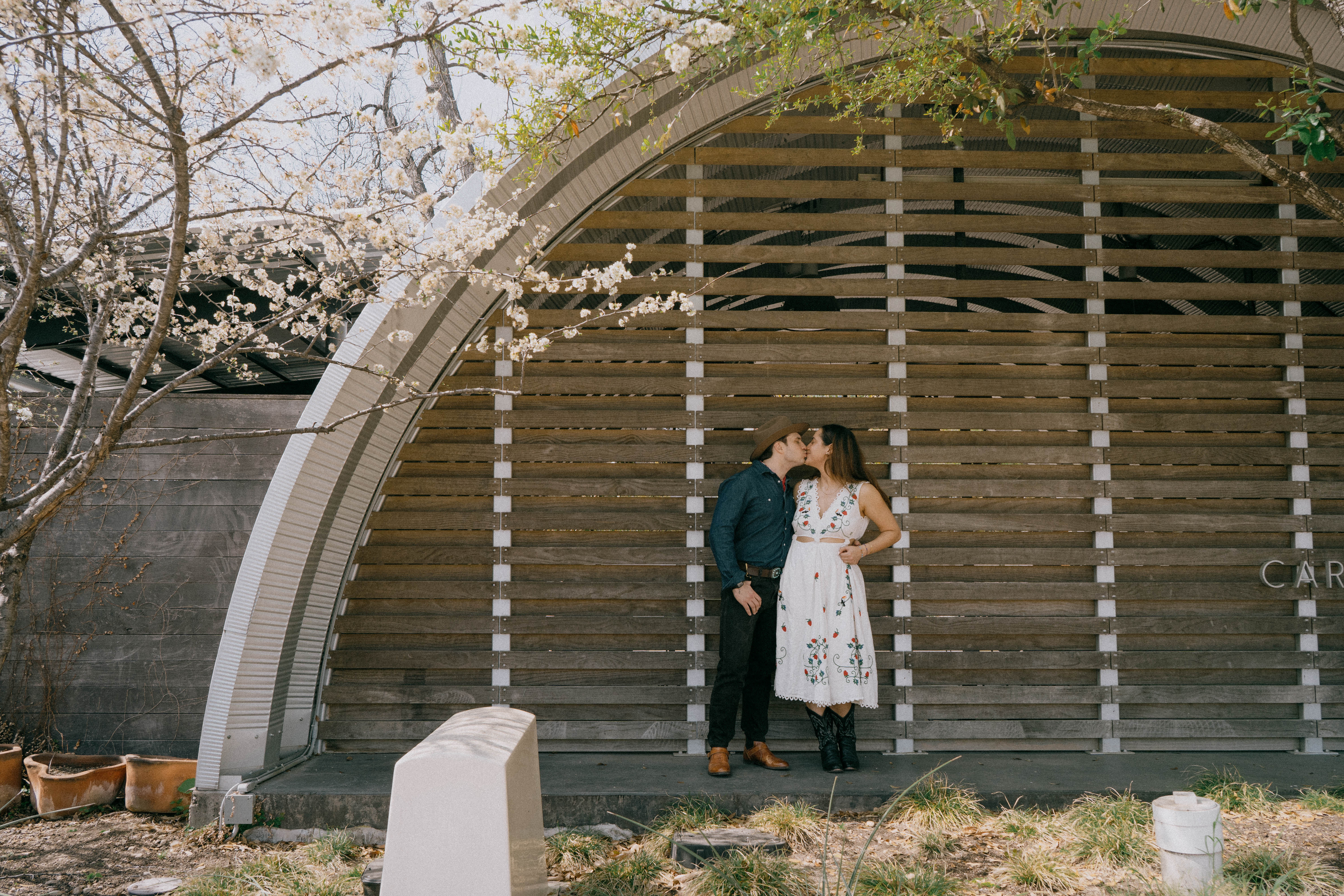 Couple kissing in front of Q-Hut at Carpenter Hotel in Austin, Texas